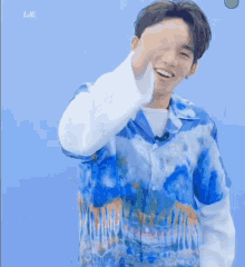 a young man wearing a blue shirt is smiling and giving a thumbs up