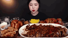 a woman is sitting at a table eating a large plate of food .