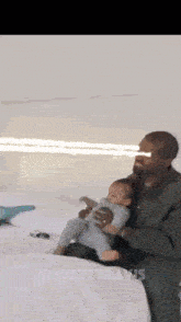 kanye west is sitting on a bed holding a baby .