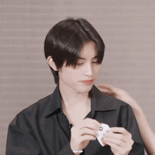 a young man in a black shirt is holding a piece of paper with a red circle on it