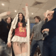 a group of people are dancing in a room with a woman wearing a red shirt that says g on it