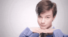 a young man in a suit and tie is making a funny face with his hands on his face .