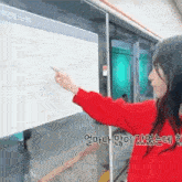 a woman in a red shirt is pointing at a map