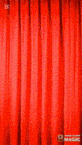 a man is taking a selfie with a microphone behind a red curtain
