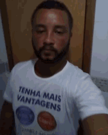 a man with a beard is wearing a white shirt that says tenha mais vantagens