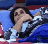 a woman is laying on a bed with a blue blanket covering her face .