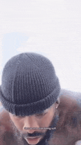 a man with a beard is wearing a black beanie and a brown jacket .
