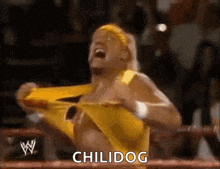 a wrestler in a yellow outfit is screaming in a ring while holding his shirt up .