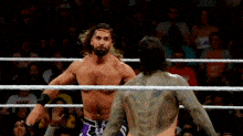 two men are wrestling in a ring with a crowd watching .