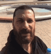 a man with a beard holds a bottle of water