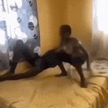 two people are standing on a bed in a room .