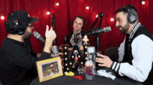 a man wearing headphones talks into a microphone while two other men look on