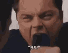 a man in a suit and tie is making a funny face and shouting .