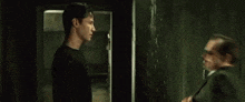 a man and a woman are standing next to each other in a dark room and looking at each other .