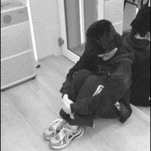 a black and white photo of a person sitting on the floor with the words " the back you all are " written on the wall behind them