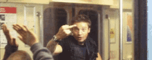a man is giving the middle finger to another man on a subway .