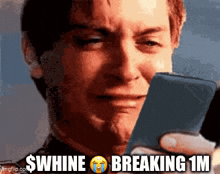 a man is crying while looking at a cell phone with $ whine breaking 1m written on it
