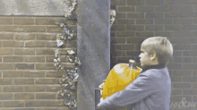 a man leaning against a brick wall with w & m written on the bottom left