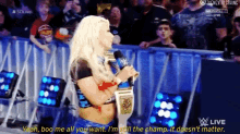 a female wrestler is talking into a microphone while wearing a championship belt