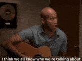 a man playing a guitar with the words " i think we all know who we 're talking about " above him