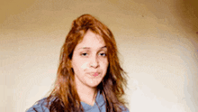 a woman with long red hair and a blue shirt looks at the camera