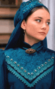 a woman wearing a blue dress with a brooch on her collar