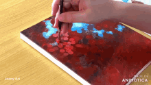a person is painting on a piece of paper that says made in animatica on the bottom