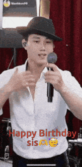 a man in a hat is singing into a microphone while wearing a white shirt .