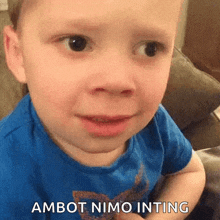a young boy in a blue shirt is making a funny face and says ambot nimo inting .