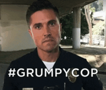 a man in a police uniform is standing in front of a sign that says #grumpycop