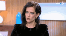 a woman in a black dress is on a tv show with the number 5 on the bottom