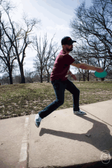 a man in a maroon shirt is throwing a frisbee on the sidewalk