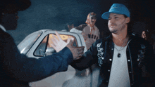 a man in a blue nike hat shakes hands with a man in a black jacket