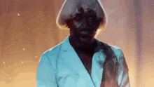 a man with a wig and a white jacket is standing in front of a fire .