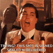 a man in a suit and tie is making a funny face while holding a bottle of wine .