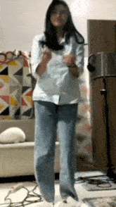 a woman in jeans and a white shirt is dancing in a living room .