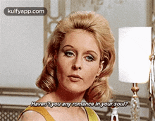 a woman in a yellow dress is standing in front of a lamp and talking to someone .
