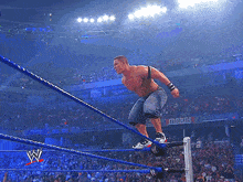 a wrestler is jumping over the ropes in front of a crowd with a sign that says march