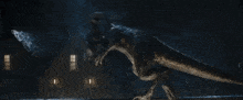 a dinosaur is flying over a building in the dark .
