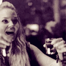 a black and white photo of a woman holding two glasses of beer .