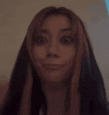 a woman with long hair is making a funny face in a dark room .