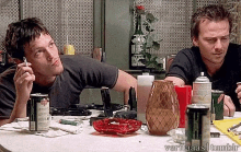 two men are sitting at a table with a bottle of jack daniels on it