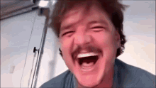a man with a mustache is laughing with his eyes closed .