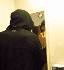 a person in a hooded jacket looking at their reflection in a mirror