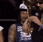 a man wearing a blue thunder jersey holds a trophy