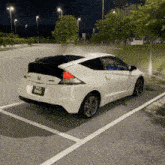 a white honda cr z is parked in a parking lot .