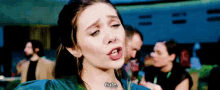 a woman is making a funny face and saying `` cute '' while sitting at a table .