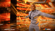 a man in a suit is dancing on a stage with a nbc logo in the background