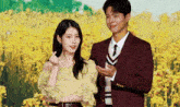 a man and a woman are standing next to each other in front of a field of yellow flowers