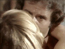a close up of a man kissing a woman on the forehead